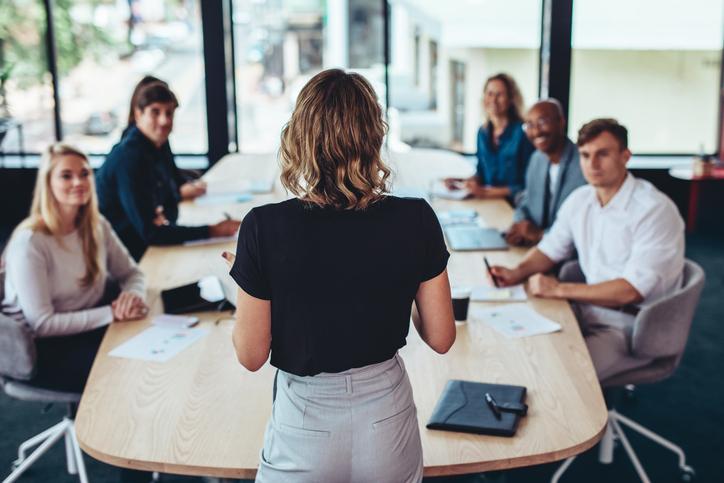 A woman is speaking in front to foster a top-notch strategy for her members that is aligned with leadership trends 2025.